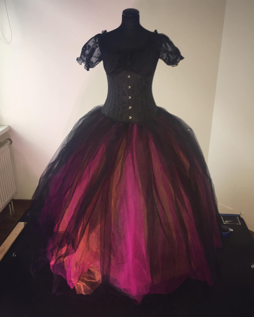 Photo of the full ballgown Emelia wore, the description is the same as the previous photo, but shows the full ballgown skirt. The skirt is pink, orange, and black tulle in overlapping layers. It is about 1.5m across with the hoop skirt and petticoats underneath.

The outfit is shown on a mannequin.