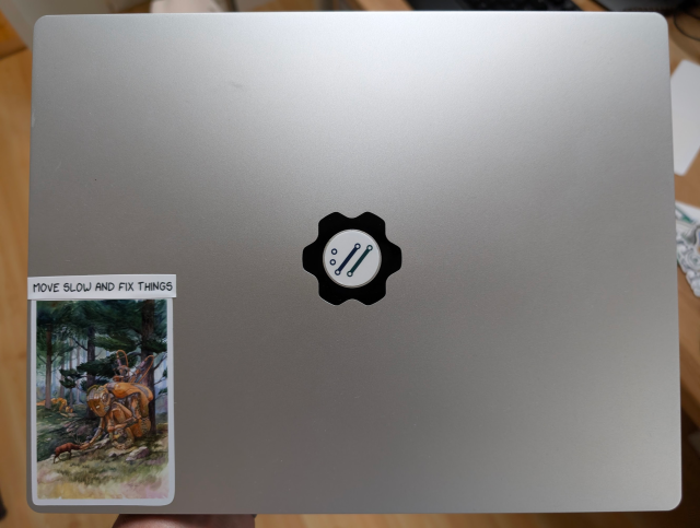My framework cover with a sticker on the lower left showing an arty sticker with a sitting giant robot golem feeding a deer in a forest.