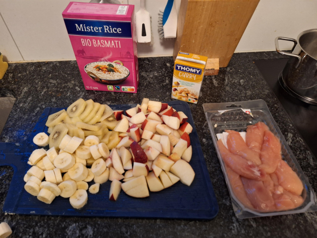 Zutaten für modifiziertes Riz Casimir. Reis, Currysauce, Goldkiwi, Bananen und Pfirsiche, Fleisch 