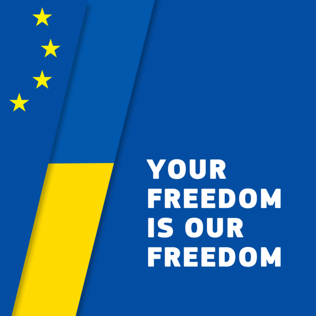 A dark blue background features a vertical yellow and blue strip on the left side, representing the Ukrainian flag. To the left of the Ukrainian flag is a vertical strip with five yellow stars, representing the European Union flag. The words "YOUR FREEDOM IS OUR FREEDOM" are written in bold, white uppercase letters on the right side of the image. 