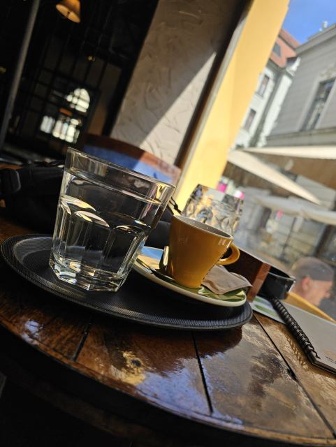v popredí espresso na drevenem okruhlom stole a tak, polliter vypitý
