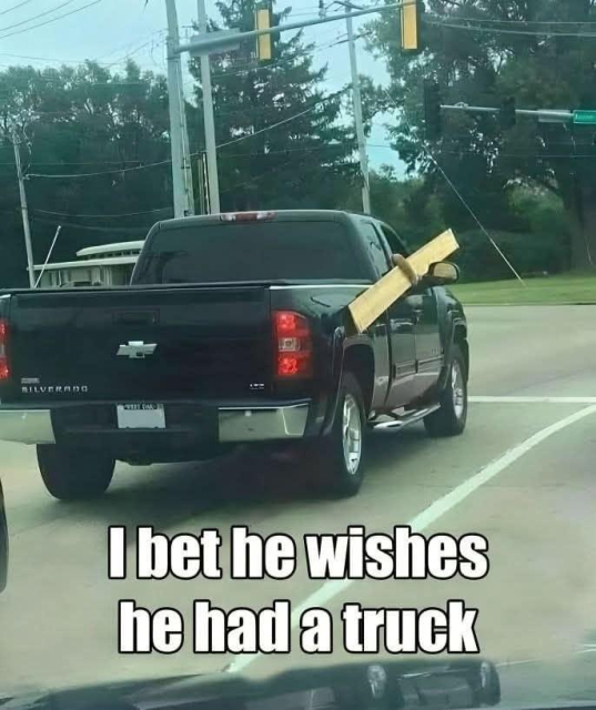 Someone driving in a pickup truck holding a plank of wood out of the window 

Text:
I bet he wishes he had a truck 
