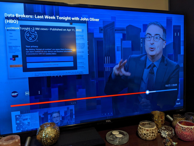 photo of television episode "Data Brokers: Last Week Tonight with John Oliver" (HBO), still at 19:17 with screenshot of website cookie notification alongside John talking. The website is Stack Exchange.
