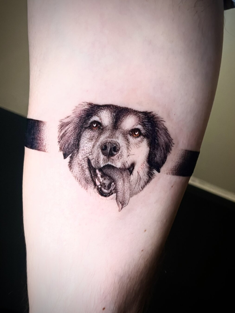 Tattoo of the face of a smiling dog with his tongue out
