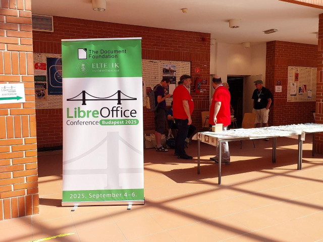 Photo of LibreOffice banner, and participants by an entrance to a talk