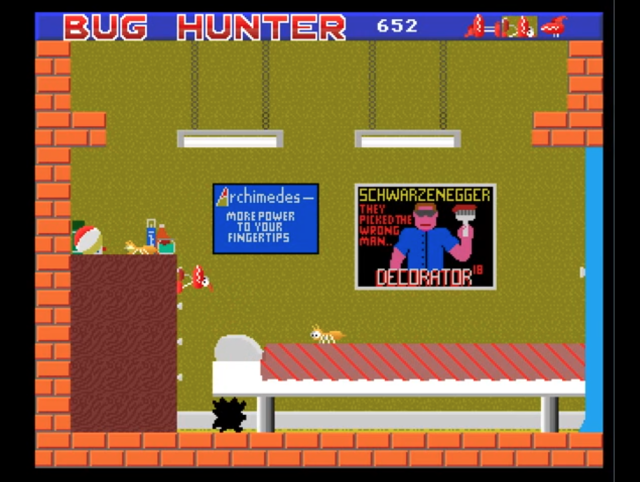 Retro video game screenshot from Bug Hunter. The scene shows a green-walled room with red brick borders. At the top, the title “BUG HUNTER” is displayed in bold red and white text, alongside the player’s score of 652. On the left, there’s a brown shelf stacked with random objects like a beach ball, bottles, and food. Below the shelf, a spiky black creature waits on the floor. A conveyor belt runs across the room, carrying a large insect. Two hanging fluorescent lights dangle from chains above. The back wall features two posters: one blue sign reads “Archimedes — more power to your fingertips,” while another is a parody movie poster showing a muscular figure with sunglasses and a paint roller, with the caption “SCHWARZENEGGER: They picked the wrong man… DECORATOR.”