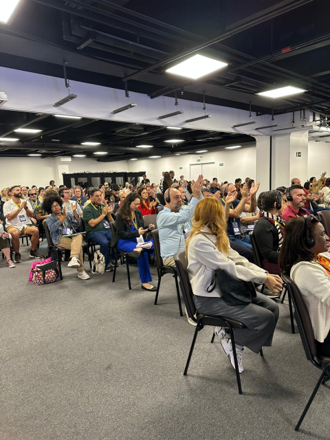 Image of the rear part of the room which is quite full with 8 rows of people seated and clapping during the "Digital Access for All – Creating Inclusive Information Spaces"