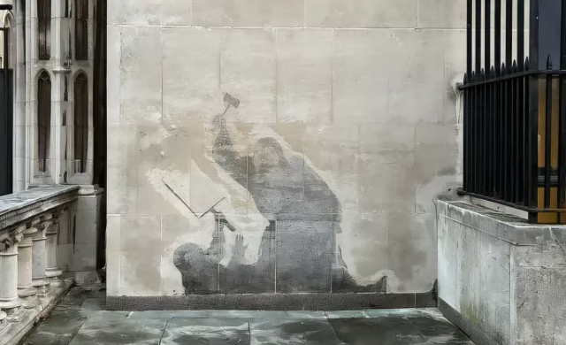 Mural on a greyish white wall. Nearby iron railings painted black. A depiction of a judge beating a person who is on the ground holding, I think, the scales of justice. It has been painted over, but a dark grey shadow remains. They look ghostly, or like shadows burned into the wall 