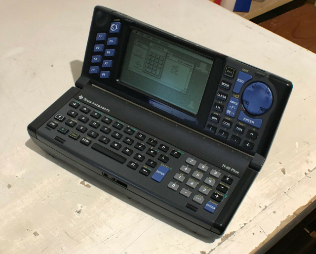 A picture of a Texas Instruments TI-92 Plus opened up, with its black & white LCD showing an install of the Mac system, running a calculator.