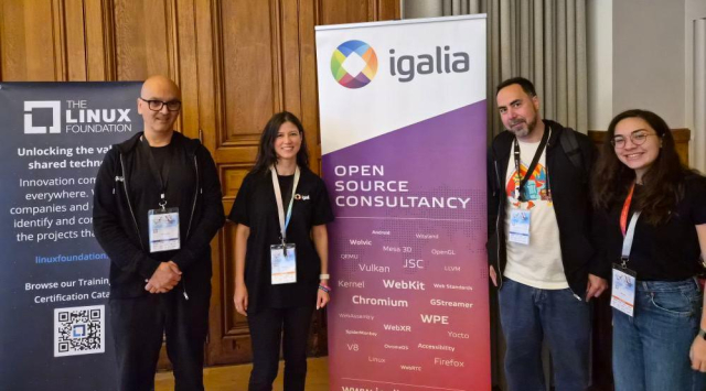 Picture of Igalians (from left to right: Luis, Melissa, Cascardo, Maíra) attending Kernel Recipes 2025 at the venue. In the background, an Igalia banner.
