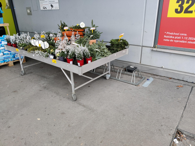 Photo from last december showing a bike stand in front of a Baumax shop entrance, which is completly blocked by a table full of Christmas decorative goods