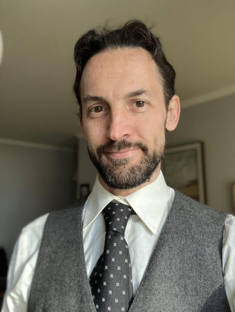 Selfie wearing a white shirt with a dark blue tie and gray wool vest.