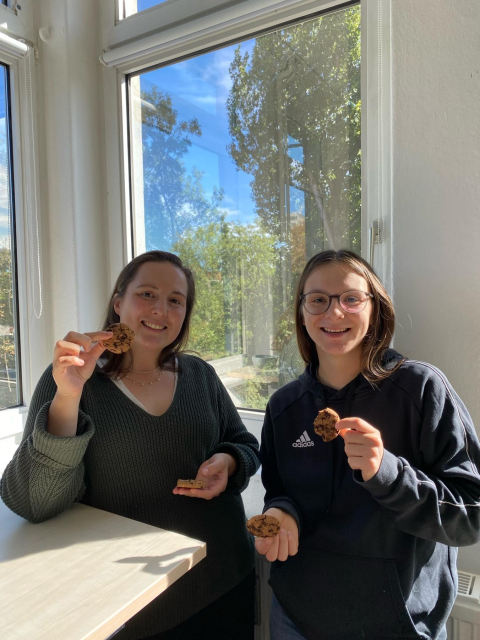 Two Tuta team members smiling while holding cookies.
