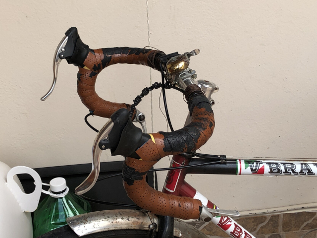 Manubrio de bicicleta, con cinta imitación piel a la que ya se le desprendió buena parte de la superficie. El hilo encerado está hecho un desastre; ha visto muchas aventuras.