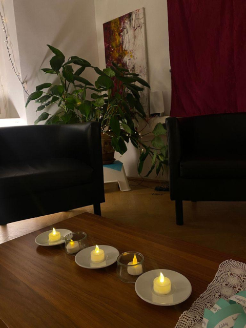 A room with comfy chairs, candles and fairy lights.
