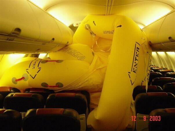 Inside of an empty passenger aircraft, with the slide fully deployed and twisted all over the place. Date on photo is 12/9/2003