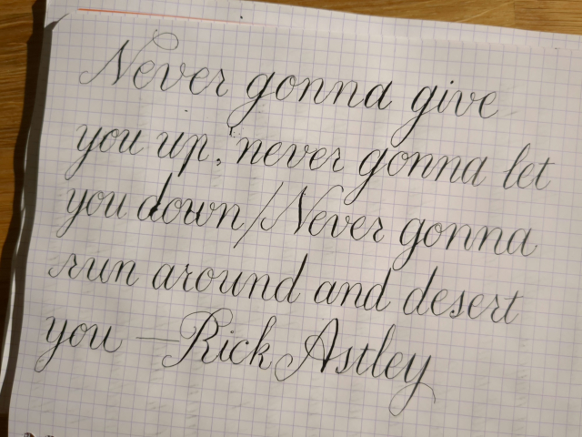 In very large, amateur English round hand on graph paper: "Never gonna give you up, never gonna let you down / Never gonna run around and desert you—Rick Astley"