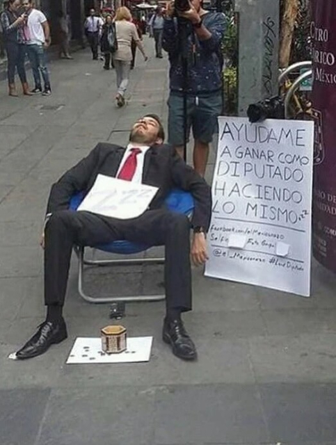 Hombre de traje durmiendo en una silla en la calle, a su lado un letrero que dice: “Ayudame a ganar como diputado haciendo lo mismo” y un botecito de lismonas
