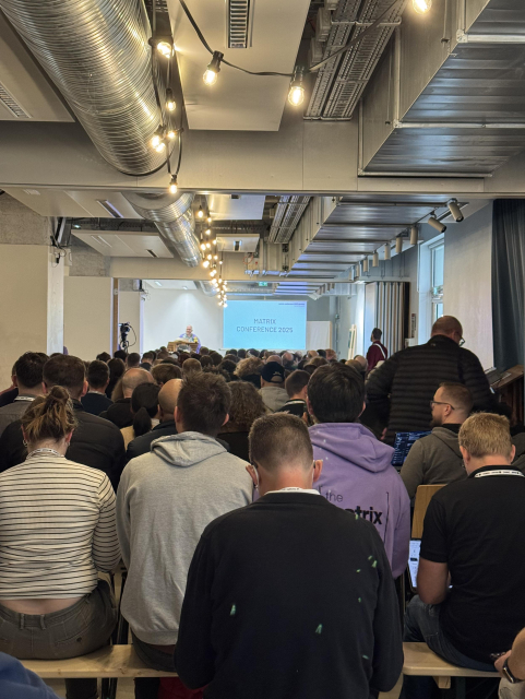 A room with plenty of people watching a talk