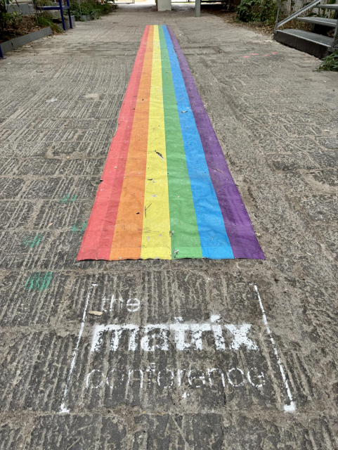 A picture of the matrix conference logo chalk sprayed next to a long pride flag.