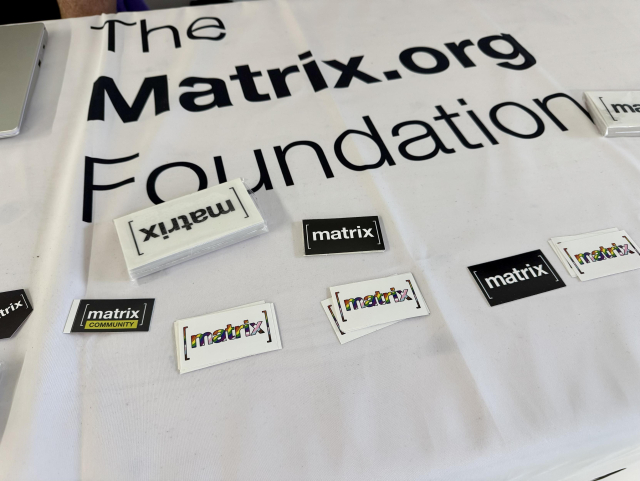 A photo of a table with stashes of stickers including ones with the colors of the progress flag