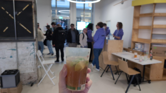 A cocktail glass in front of blurry people gathering together in front of the cocktail bar.