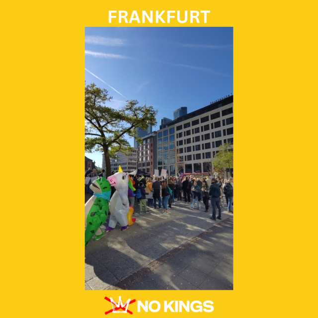 A photo of dozens of people at the No Kings protest in Frankfurt, Germany. A person in a frog costume is shown walking alongside a person in a unicorn costume.