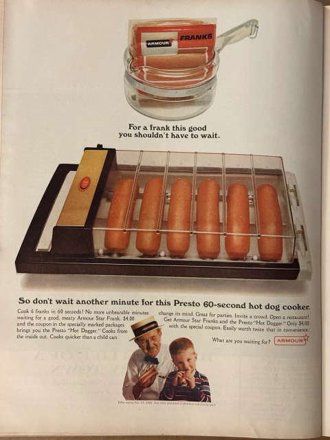 In this image, we see a rectangular device with a clear top. Inside this clear box are six hot dogs. This appliance will send electrical currents through each end of the hotdog, essentially electrocuting them while heating them up.