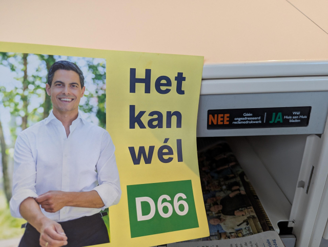 Een het kan wél flyer naast een brievenbus met Nee - Ja sticker
