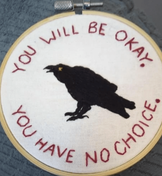 A needlepoint of a corvid cawing, with the words: You will be okay. You have no choice.