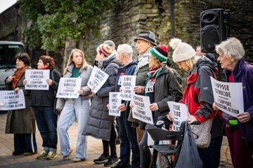 A row of people holding placards reading I OPPOSE GENOCIDE, I SUPPORT PALESTINE ACTION