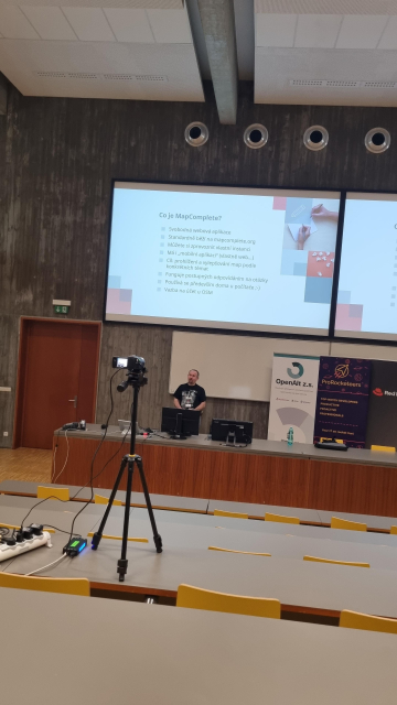 White male in front of a screen. The screen is about MapComplete.