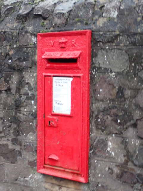 A red postboxes with a VR royal cypher mounted in a stone wall