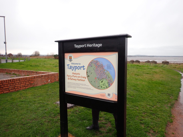 An information board about Tayport local heritage located on a grassy sward above the shore.