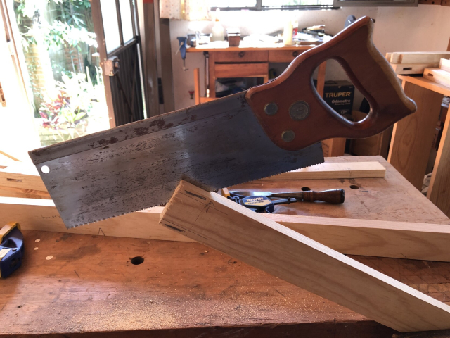 Un serrucho de costilla, de corte longitudinal, a medias de cortar una espiga en el extremo de un travesaño para el zapatero.