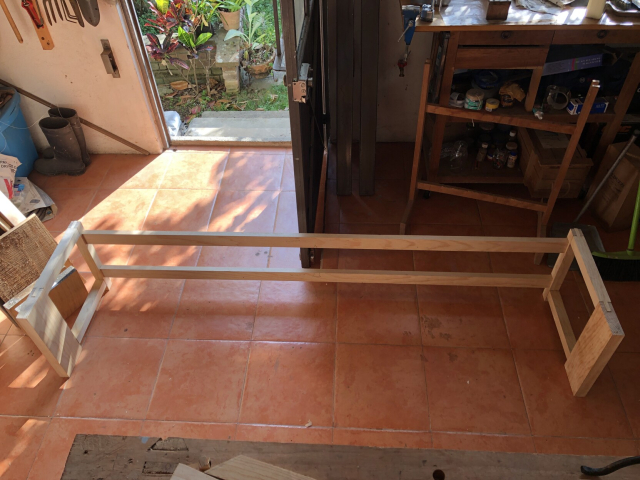 El marco del zapatero armado, sin pegar, sobre el piso del taller. Por la puerta abierta entra la luz de la tarde desde el jardín.