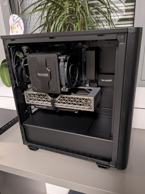 An opened PC case with silver GPU and a massive black CPU cooler. The whole configuration is black except for the silver GPU.