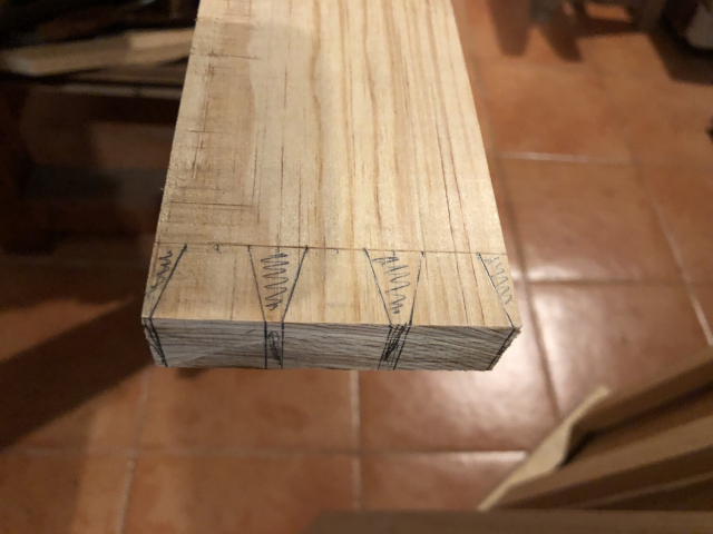 El extremo de una tira de madera, marcada con colas de milano para cortar después