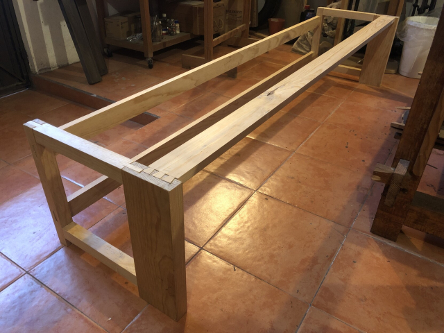 El armazón del zapatero ensamblado, sin pegar, sobre el piso del taller. A lo largo del frente hay una pieza que une los extremos con colas de milano.