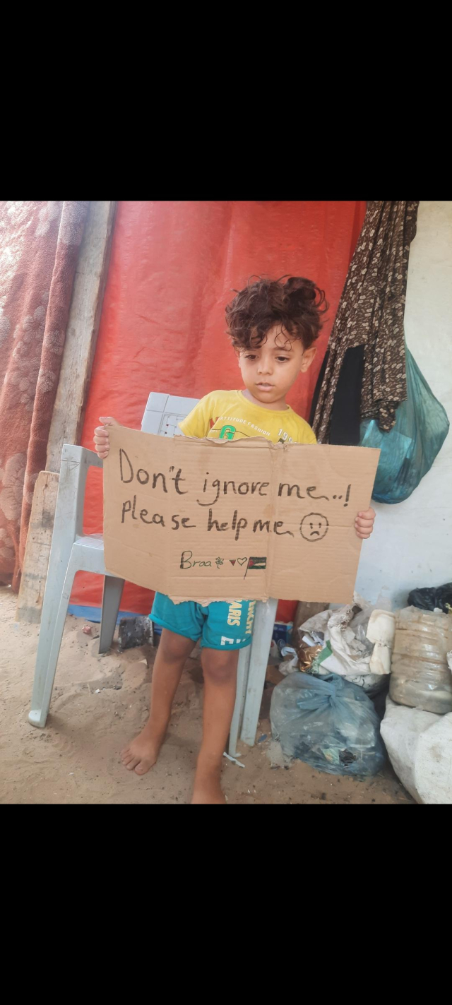 My four-and-a-half-year-old son, Ibrahim, is standing in the tent holding a sign that reads, "Please don't ignore me and help me."