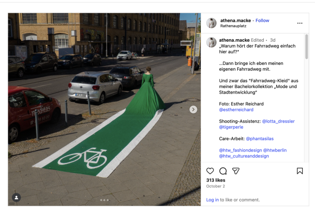A woman wearing a green ballgown walks down a sidewalk in a city. Cars are parked along the curb. The train of the dress forms a cycle lane, with white lines along the green and a white icon of an upright bicycle at the end of the train. The designer is Athena Macke and they comment "Warum hört der Fahrradweg einfach hier auf?“

…Dann bringe ich eben meinen eigenen Fahrradweg mit. 

Und zwar das "Fahrradweg-Kleid" aus meiner Bachelorkollektion „Mode und Stadtentwicklung“ "

"Why does the bike path just end here?

…Then I'll just bring my own bike path.

Specifically, the "bike path dress" from my bachelor's collection "Fashion and Urban Development."'
