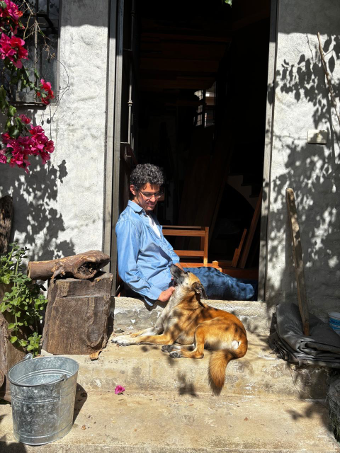 Gaia echada en los escalones del jardín al taller; yo sentado atrás de ella. Nos da el sol del medio día. Se ve una bugambilia y el tronco que utilizo para el hacha.