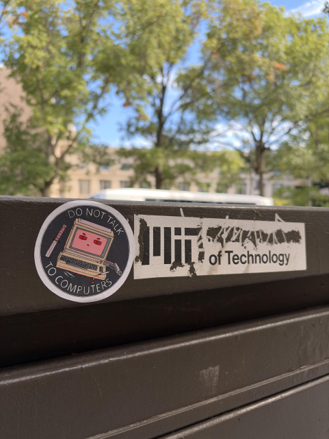 Sticker on a black pole that reads "Do not talk to computers" with a drawing of a retro computer, a knife, and a gun.