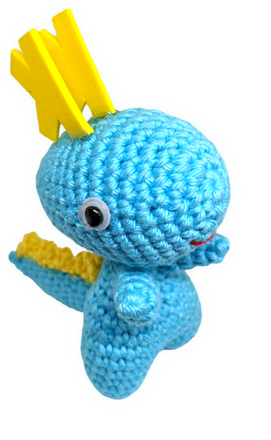 A cute, cheeky-looking aqua-blue amigurumi dragon called "Karmen" looks into the camera.