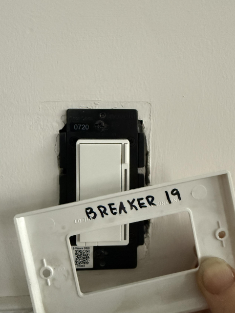 Light switch with the cover off, with “breaker 19” written in marker on the back of the cover