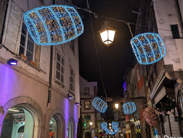 Christmas lights in the shape of barrels hanging above a narrow street