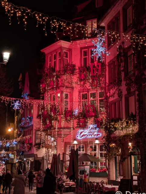 A building illuminated in vivid red with gold lights strung across the street.