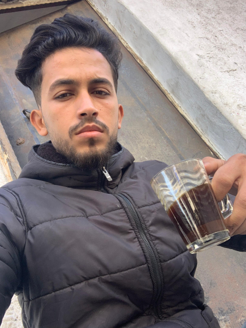 Mohammed Shobair, 23 years old, from Gaza, Palestine, holding a cup of coffee before me.