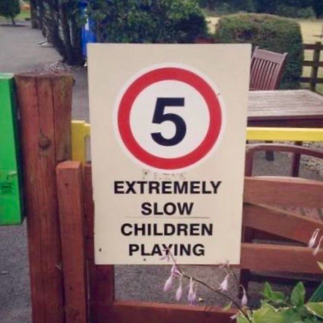 Speed caution sign with a 5 circled in red, followed by “EXTREMELY SLOW CHILDREN PLAYING.”