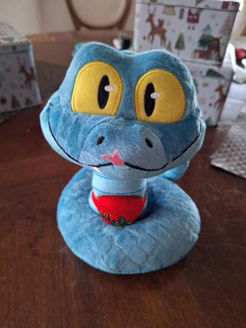 Eine kleine blaue Plüschschlange mit roter Spaltzunge, gelben Augen und roter Bauchtasche 